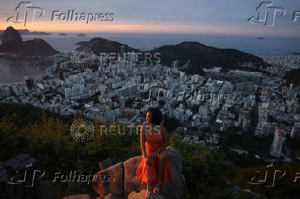 A woman poses for a photo during sunrise at Dona Marta lookout point in Rio de Janeiro