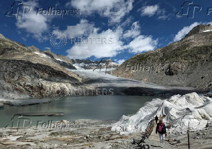 Tourists walk to the entrance of the ice cave covered with fleece blankets, to slow down melting, amid climate change in Obergroms