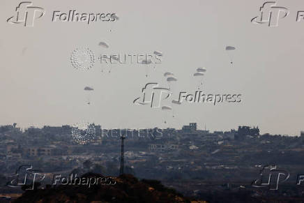 Aid packages dropped from an airplane descend over Gaza Strip, as seen from Israel