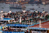 People board passenger ferries as they leave to celebrate Eid al-Adha with their families, in Dhaka