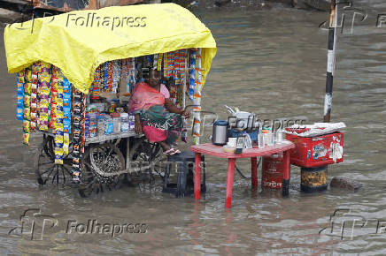 A woman vendor sits in her shop cart, as streets are flooded after torrential rain, in Ahmedabad