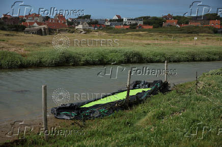 A destroyed inflatable used to smuggle migrants across the English Channel lies on the side of a water channel near the beach in Ambleteuse