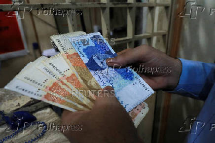 FILE PHOTO: A man counts Pakistani rupee notes at a currency exchange shop in Peshawar