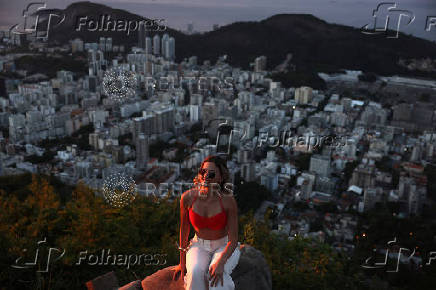A woman poses for a photo during sunrise at Dona Marta lookout point in Rio de Janeiro