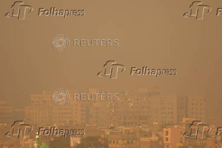 Pigeons fly past residential buildings amid smog and air pollution in the morning in Karachi