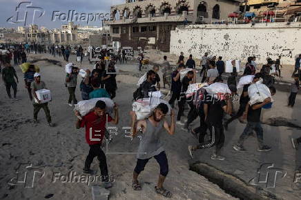 Displaced Palestinians carry relief parcels along Rashid Street, west of Gaza City