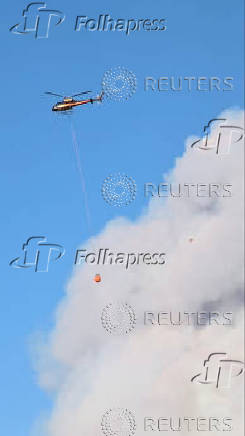 A firefighting helicopter operates as smoke billows from the White Sage Fire, in Fredonia