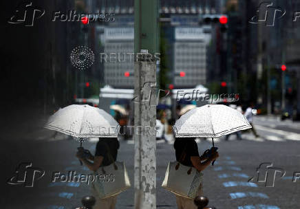 A woman holding a parasol walks on the street in Tokyo