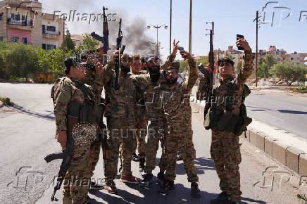 Members of Syrian security forces stand together and use their mobile phones after Syrian troops entered the predominantly Druze city of Sweida