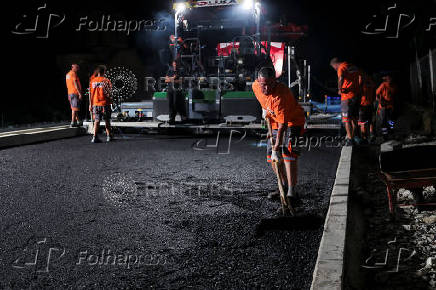 Workers lay asphalt at night to avoid the daytime heat wave, in Rahovec