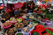 Vendors work at their fruit and vegetable stalls inside a market, in Dong Dang township