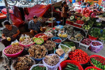 Vendors work at their fruit and vegetable stalls inside a market, in Dong Dang township