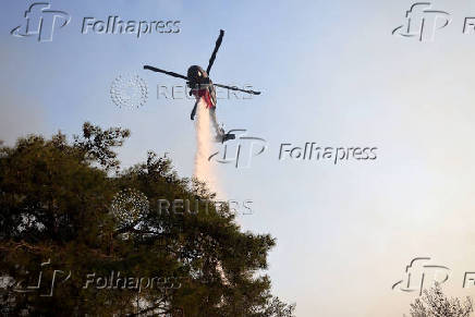 A firefighting helicopter drops water to extinguish fire at the area of Souni near Limassol,
