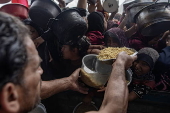 Displaced Palestinians collect donated food in Khan Yunis, southern Gaza