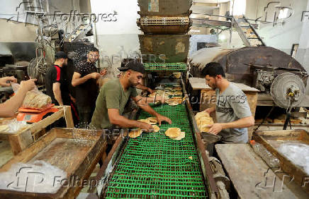 Palestinian workers make bread in a bakery that returned to operation after being closed due to a flour shortage, in Deir Al-Balah