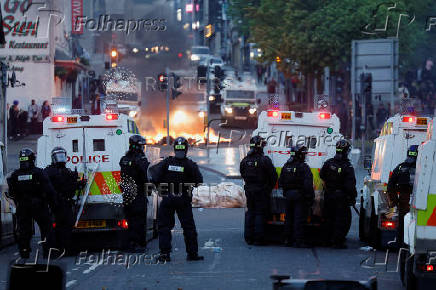 Armed police in riot gear stand guard during a second night of riots, in Ballymena