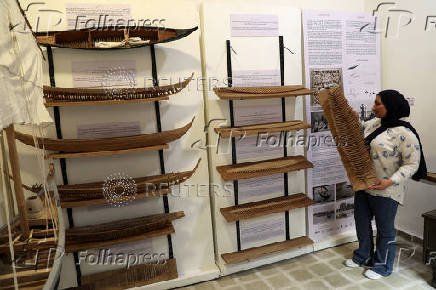 A tour guide arranges small boat models inspired by Sumerian and Babylonian designs at the Manuscripts and Basra Heritage Center in Basra