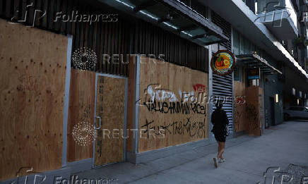 A person walks past stores boarded as a protection amid protests against federal immigration sweeps, in Los Angeles