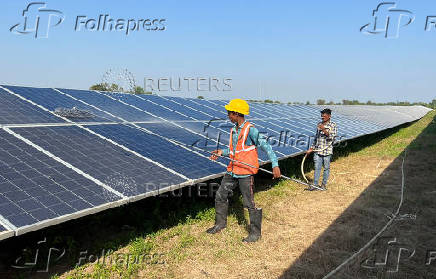 FILE PHOTO: Workers clean panels at a solar park in Modhera