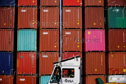 FILE PHOTO: FILE PHOTO: A truck driver works in front of shipping containers stacked up at Pusan Newport Terminal in Busan