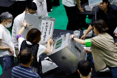 Election officials open ballot boxes during Japan's upper house election at a counting centre in Tokyo