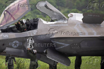 A U.S. Marine Corps pilot sits in the cockpit of an F-35 fighter jet as a ground crew member assists after the plane landed at the former Roosevelt Roads military base in Ceiba