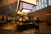A tourist takes photos of museum exhibits displayed at the Grand Egyptian Museum
