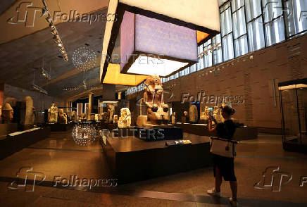 A tourist takes photos of museum exhibits displayed at the Grand Egyptian Museum