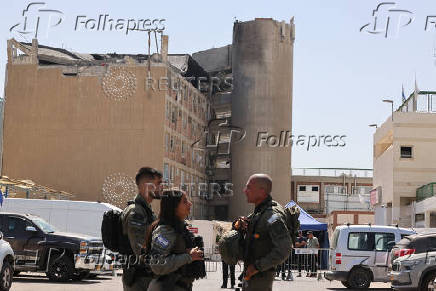 Members of the Israeli security forces stand near the Soroka Medical Center, after it was hit by a missile fired from Iran, in Beersheba