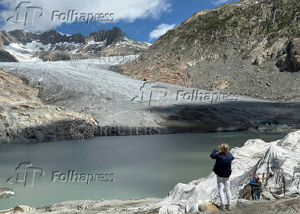 A woman takes a picture of the Rhone glacier amid climate change in Obergoms