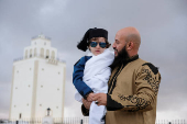 A man looks at his son as they celebrate Eid wearing traditional Libyan outfits in public gathering in Benghazi