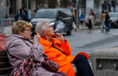 Two elderly women smoke cigarettes as they sit on a bench in Moscow