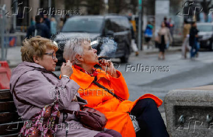 Two elderly women smoke cigarettes as they sit on a bench in Moscow