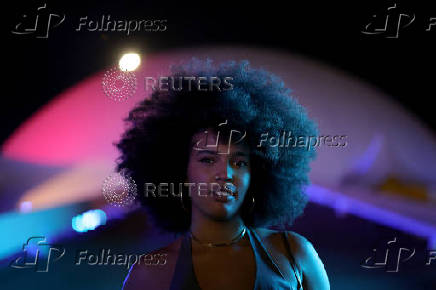 A woman with an afro hairstyle poses for a portrait in front of the 