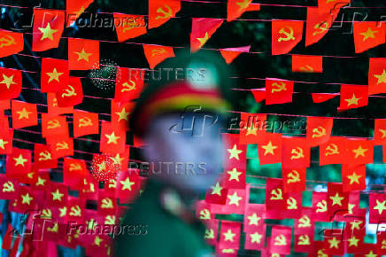 A police officer stands in front of red flags used to decorate a street, in Hanoi