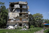 A resident walks at a street near a building damaged by Russian military strikes in the frontline town of Kostyantynivka