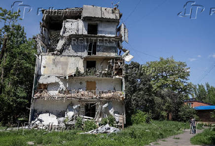 A resident walks at a street near a building damaged by Russian military strikes in the frontline town of Kostyantynivka