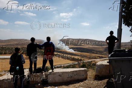 Palestinians watch a burnt farm, after an Israeli settlers attack in Al Mughayyir near Ramallah