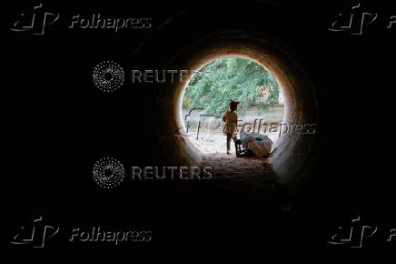 A child stands inside a makeshift tunnel made from a truck cargo trailer buried under dirt, where they hide when a rocket siren alert sounds for a missile strike from Iran on Israel, in southern Negev