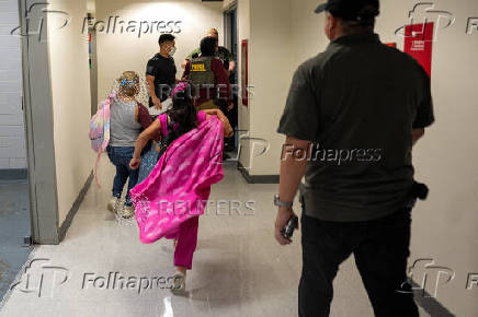 The wife and daughter of a detained migrant chase him as he is taken to a stairwell at U.S. immigration court in Manhattan