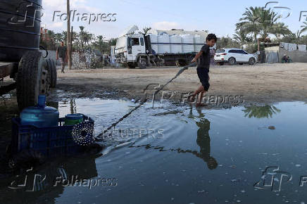 Palestinians collect water amid shortages, at a distribution point in Deir al-Balah in the central Gaza Strip