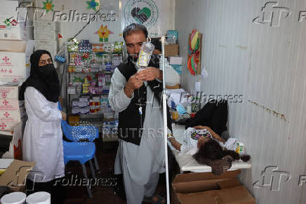 An Afghan doctor treats a girl, who was deported from Iran, inside a mobile clinic at a camp for returning migrants near the Islam Qala border crossing