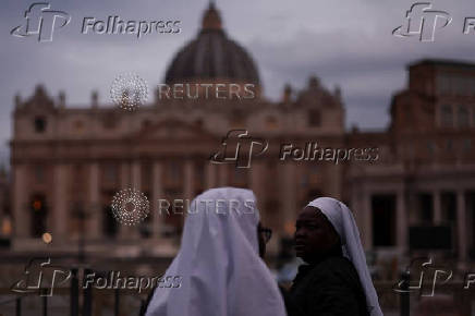Nuns stand in front of St. Peter's Basilica, at St. Peter's Square in the Vatican
