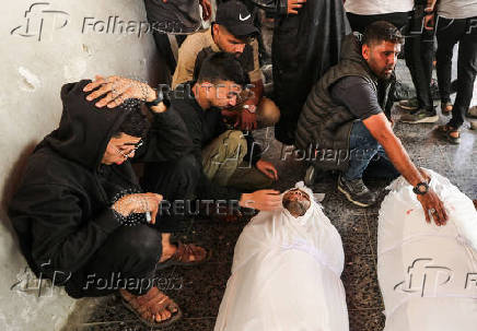 Mourners sit next to the bodies of Palestinians killed in Israeli strikes, at Al-Ahli Arab Baptist hospital, in Gaza City