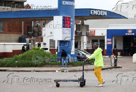Man walks past a gas station, in Harare