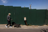 A man walks his dog near the Ukrainian Motherland Monument in Kyiv