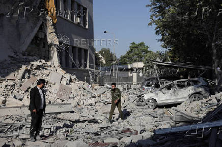 People gather near a damaged site, in Damascus