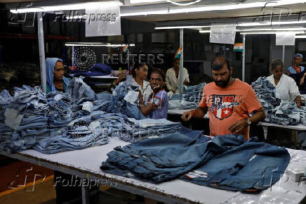 Workers make final checks on jeans pants before packaging in a garment manufacturing unit on the outskirts of Ahmedabad