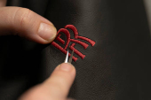 A technician repairs the logo by hand at the leather workshop line for Rolls-Royce vehicles at Rolls-Royce Motor Cars' manufacturing plant in Goodwood