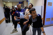 A paramedic carries a Palestinian man wounded in an Israeli strike, at Nasser Hospital, in Khan Younis